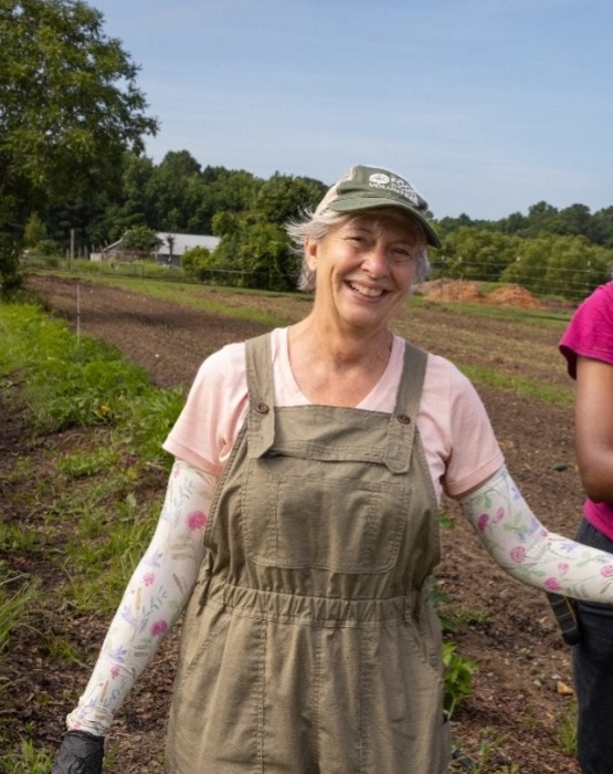 Photo of Food Shuttle volunteer, Beth Melcher, at the Food Shuttle Farm posing for a photo at a Farm volunteer shift.